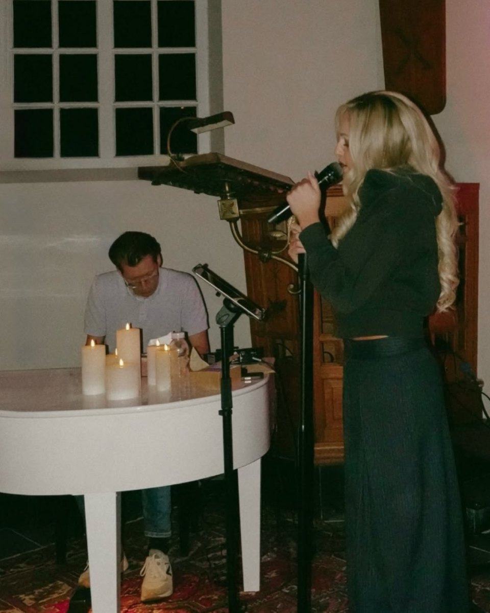 Zangeres Vonne zingt bij een witte piano met kaarsen