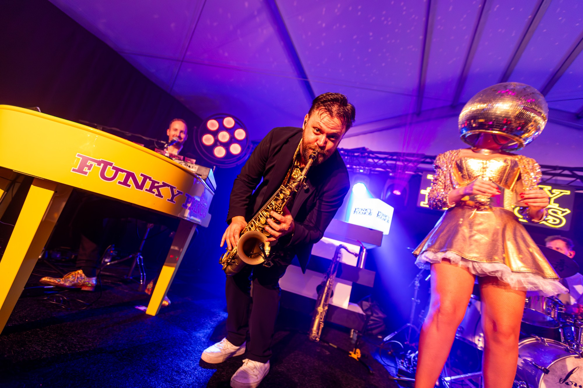 De saxofonist van Funky Pianos naast een Golden Mirror Girl met discobolhoofd