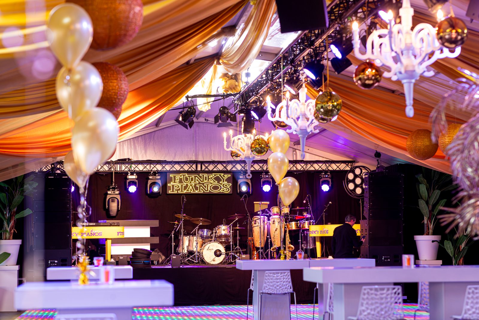 Het podium van Funky Pianos XXL in een feesttent met gouden ballonnen