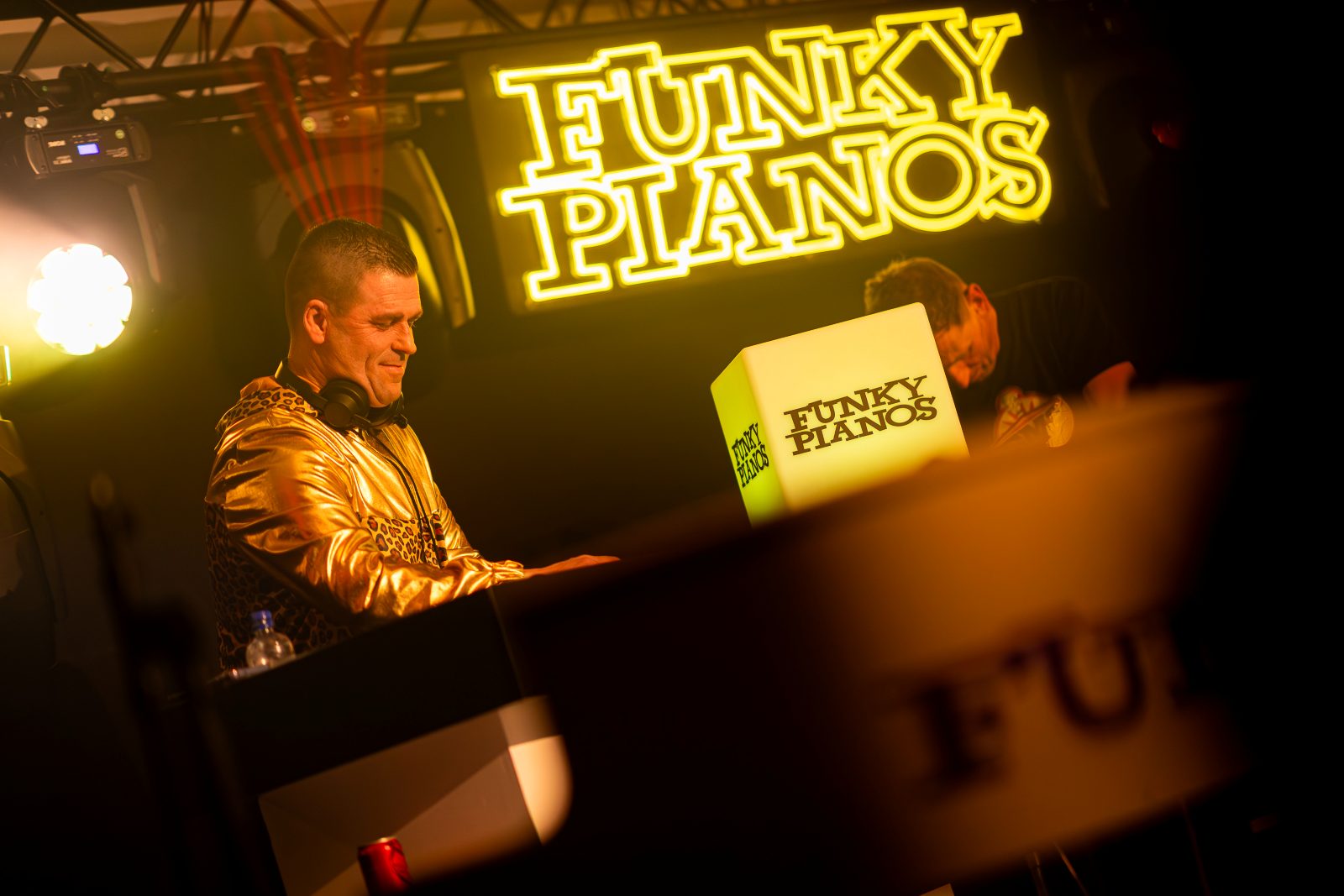 De pianist van Funky Pianos in een gouden jasje achter zijn piano