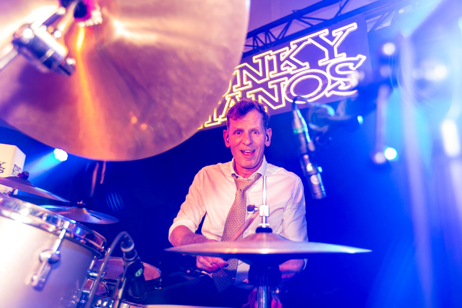 De drummer van Funky Pianos achter zijn drumstel onder het podiumlicht