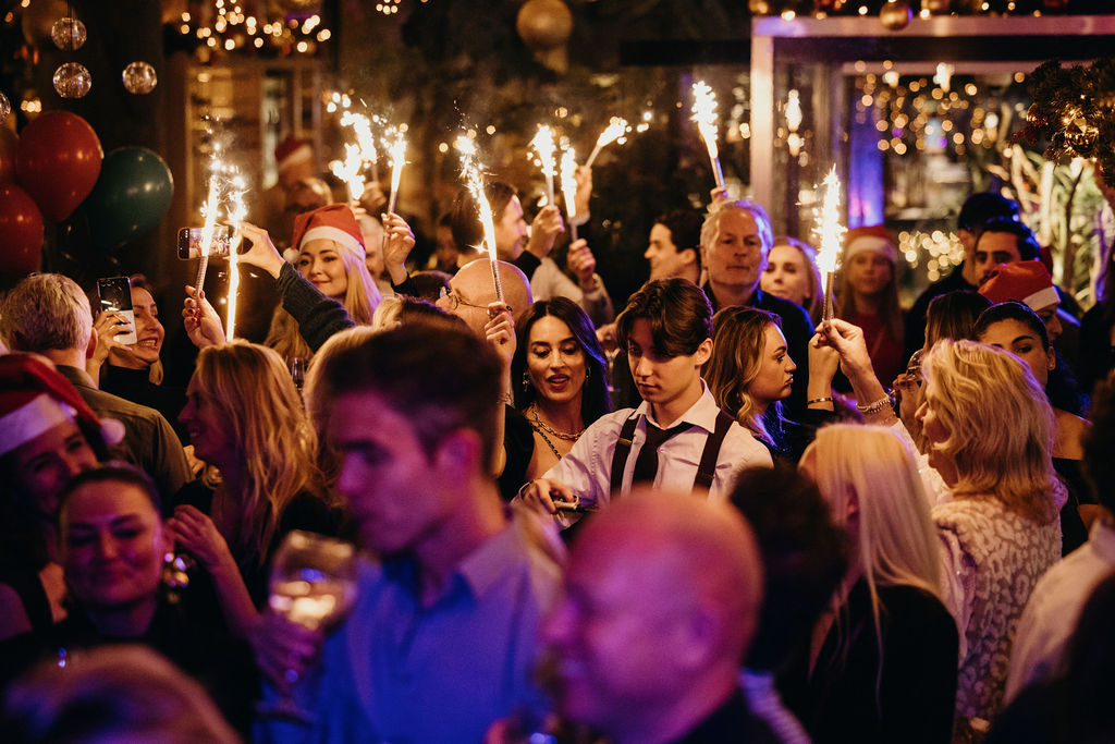 Gasten in kerstmutsen houden brandende sterretjes omhoog tijdens de Christmas Edition van de Slaak Sunday Brunch